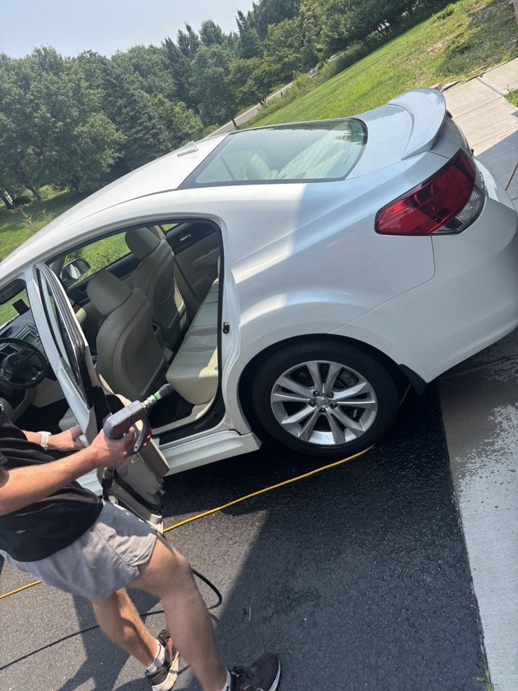Vertex detailer working on a white sedan in a customer's driveway